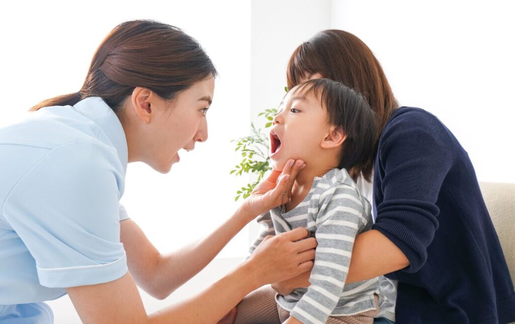 母親に抱かれた男の子の口腔内を歯科医がチェックしている様子
